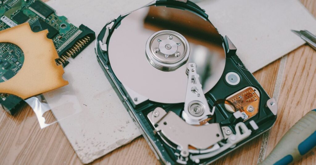 Close-up of a disassembled hard drive showing internal components on a wooden table.