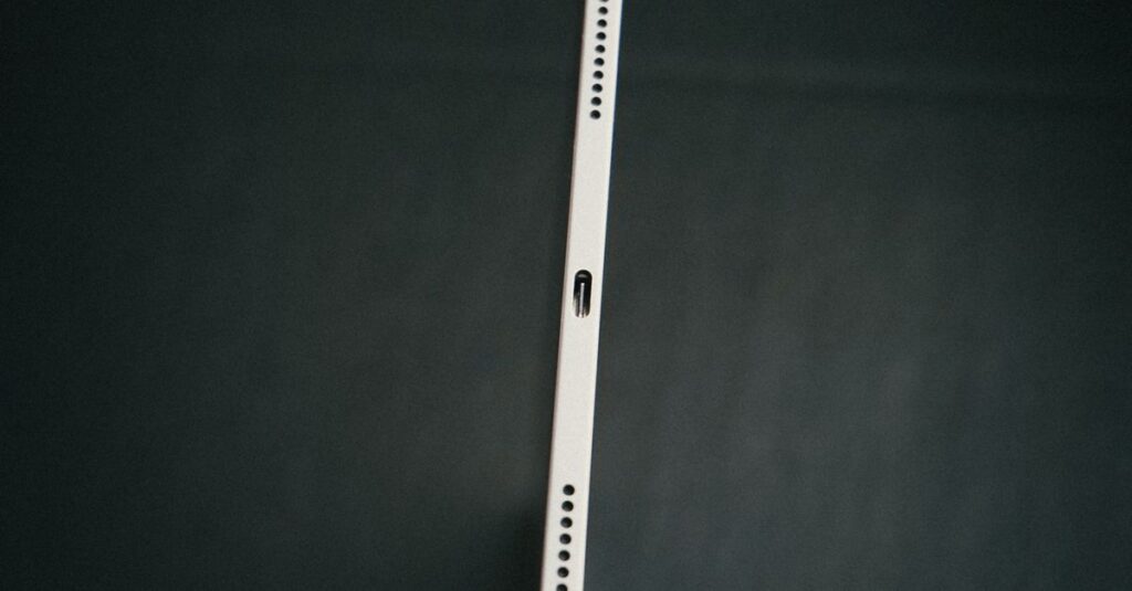 Close-up of a hand holding a slim tablet against a dark backdrop, emphasizing technology's sleek design.