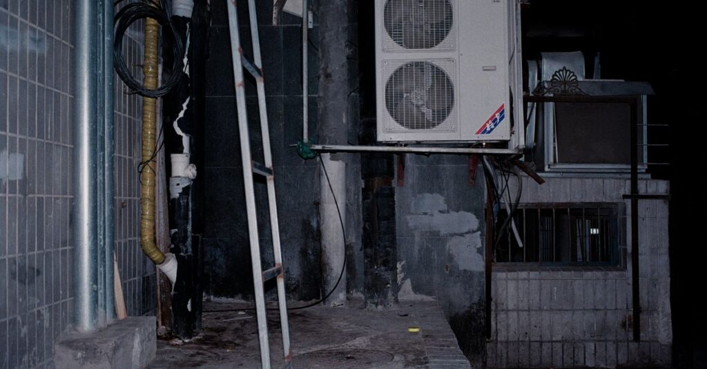 Close-up of an industrial air conditioner setup on a building wall, showcasing pipes and a ladder.