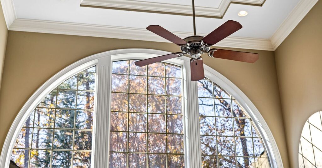 Spacious interior featuring an arched window and decorative ceiling fan with natural light.