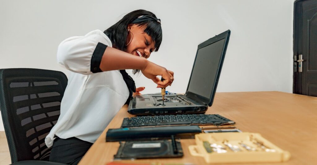 Woman repairing a laptop at a desk with tools, showcasing technology and skill.