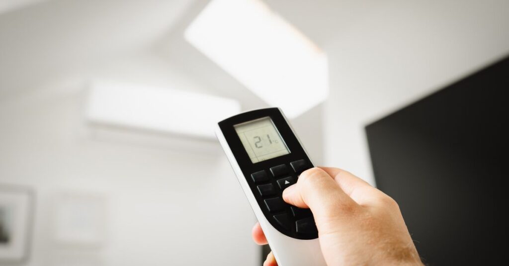 Close-up of a man using a remote to control air conditioning indoors.