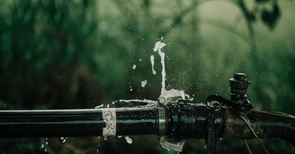 A detailed view of a leaking water pipe in a lush green garden setting.