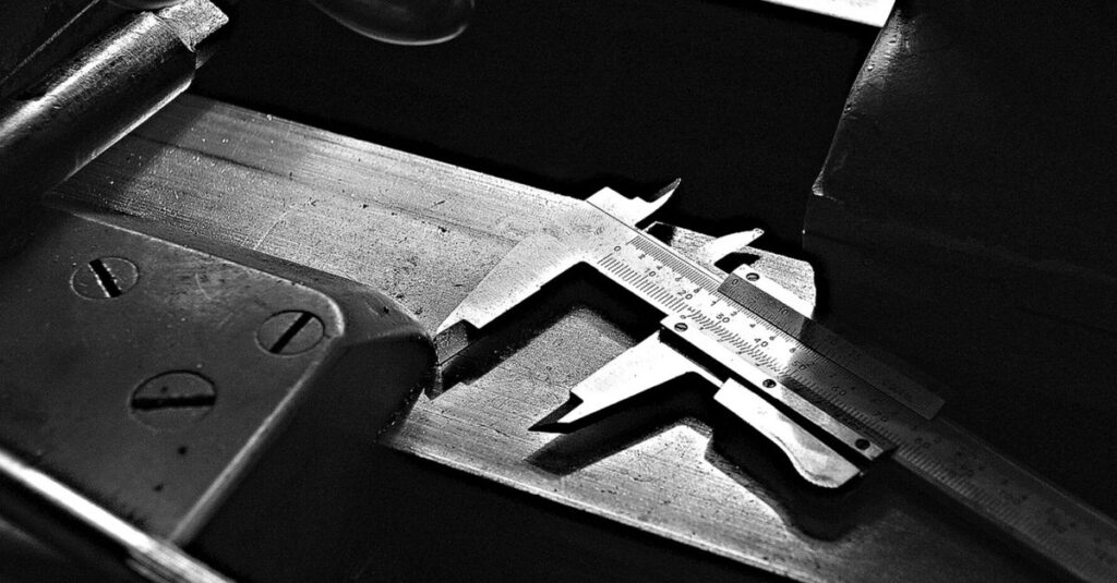 A detailed black and white image of a caliper tool on a workshop table, highlighting precision.