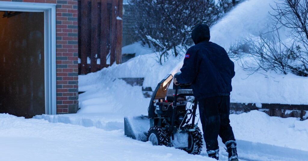 A person using a snow blower to clear snow from a suburban sidewalk in Toronto during winter.