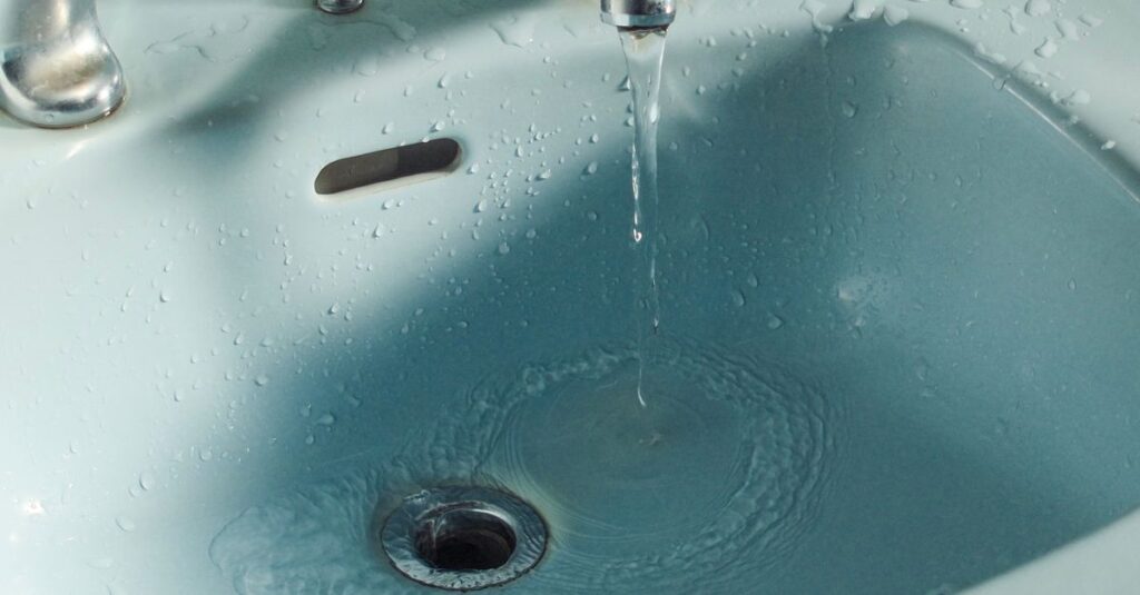 Close-up of water flowing from a faucet into a bathroom sink.