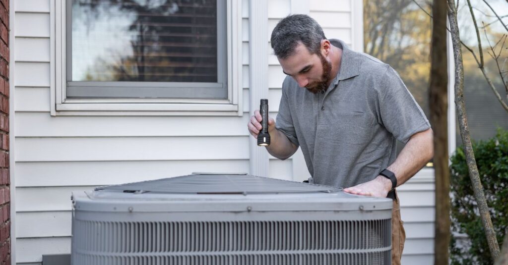 A technician inspects an outdoor HVAC unit for maintenance.