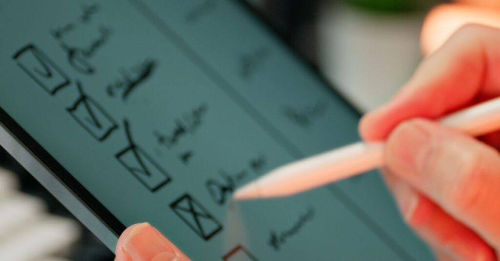 Close-up of hands using a stylus to write on a digital checklist, enhancing productivity.