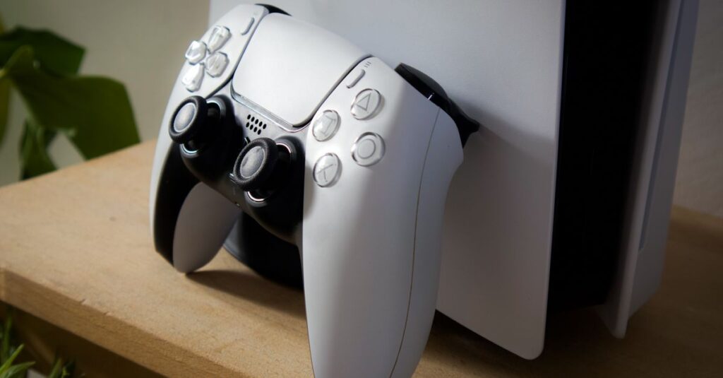 Close-up of PlayStation 5 with DualSense controller on a wooden shelf.