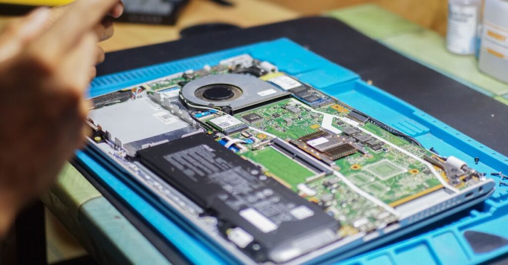 Close-up of laptop being repaired with visible components and tools.