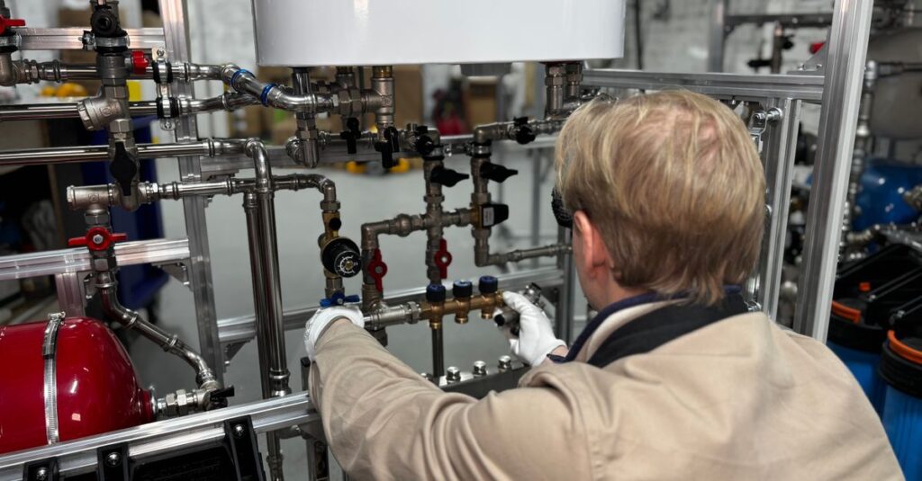 Engineer working on industrial pipe system in a factory for heating and production adjustment.