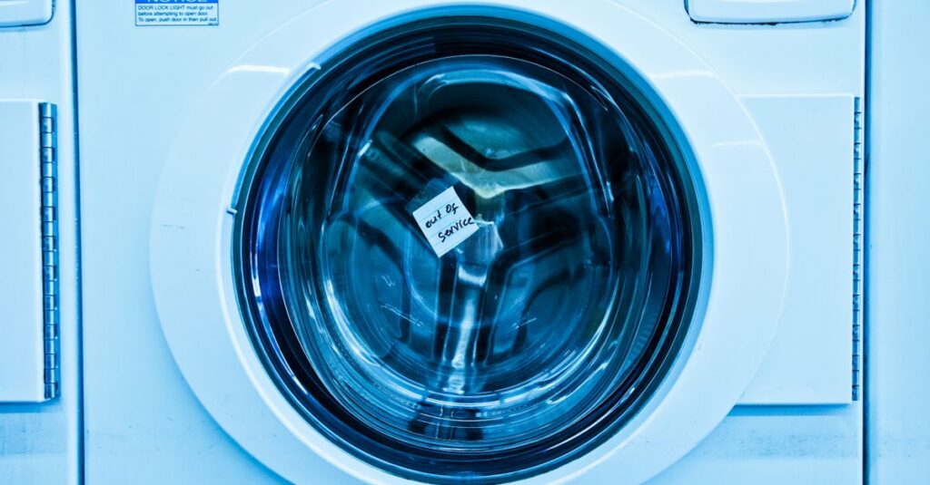 Close-up of an out-of-service washing machine in a laundromat with a blue tint.