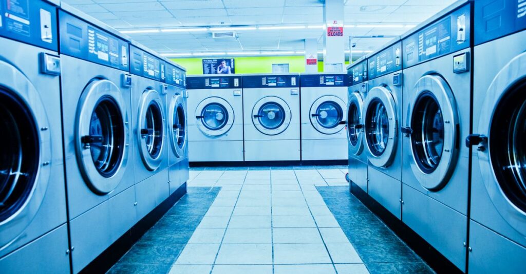 A contemporary laundromat with rows of industrial washing machines and bright interior lighting.