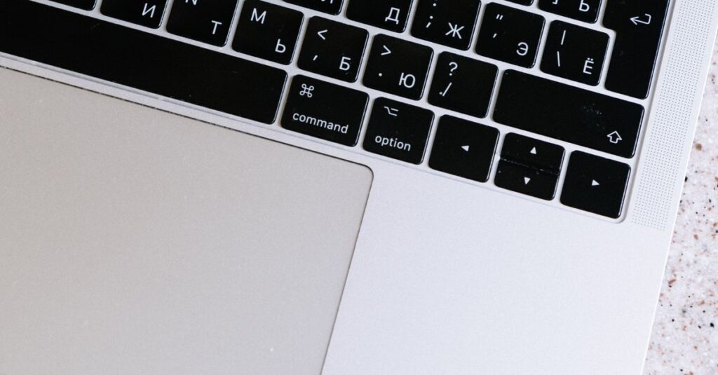 Overhead shot of a modern laptop with Cyrillic keyboard on a textured surface.
