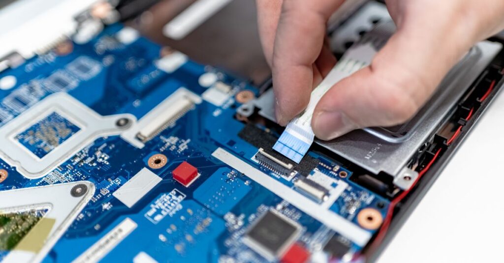 Close-up image of hands repairing a laptop circuit board showing intricate details of electronics.