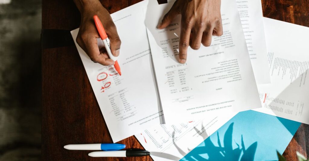 Overhead view of hands highlighting financial documents on a desk.