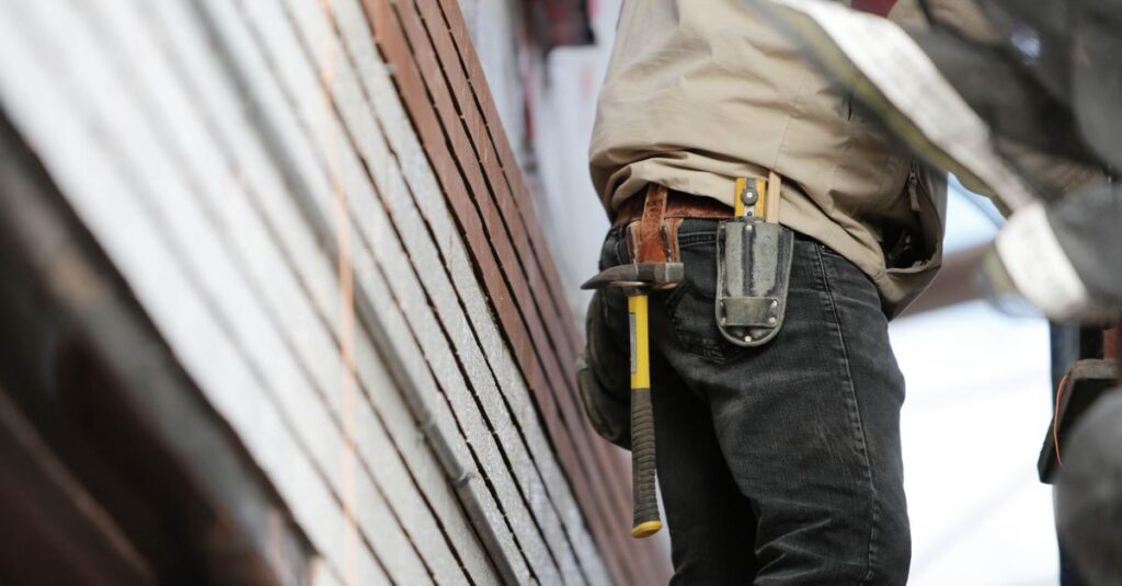 Close-up of a construction worker with hammer and tools, focused on the job.