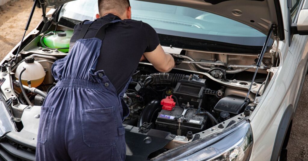 Close-up of mechanic repairing a car engine. Outdoor setting during the day.