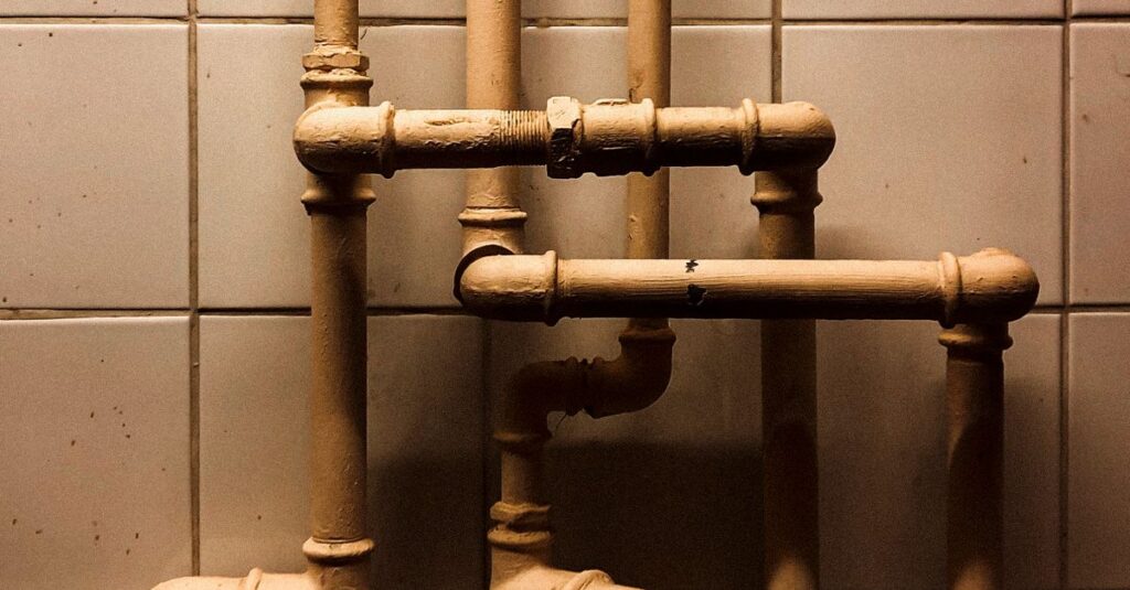 An artistic capture of vertical industrial pipes against a tiled wall, showcasing geometry.