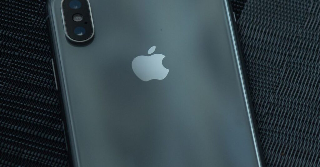 Close-up of a sleek iPhone on a textured dark surface, highlighting its design.